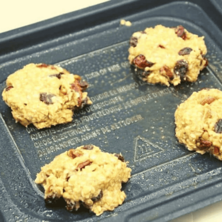 Scooping cookie dough onto parchment-lined air fryer basket ready to cook.