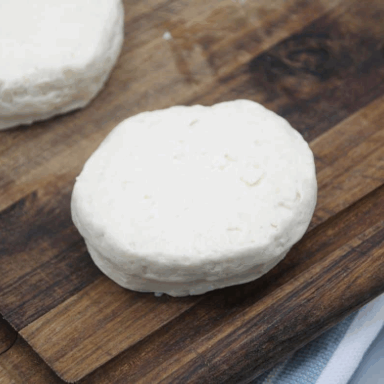 Refrigerated biscuits removed from the package and laid out on a cutting board.