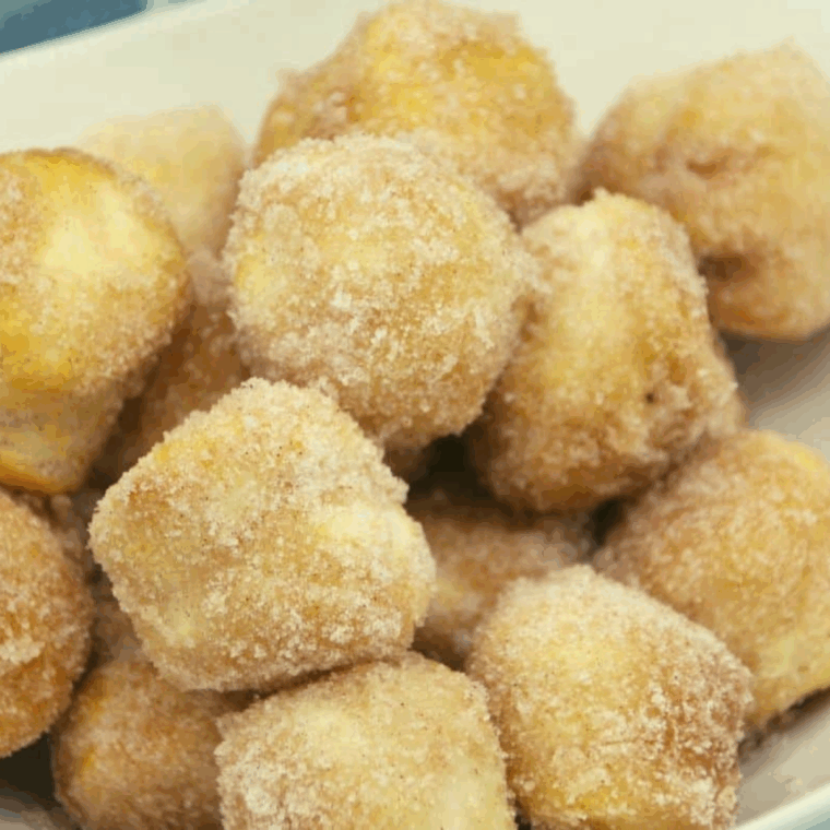 Golden, fluffy Copycat Duck Donuts donut holes coated in cinnamon sugar on a plate.