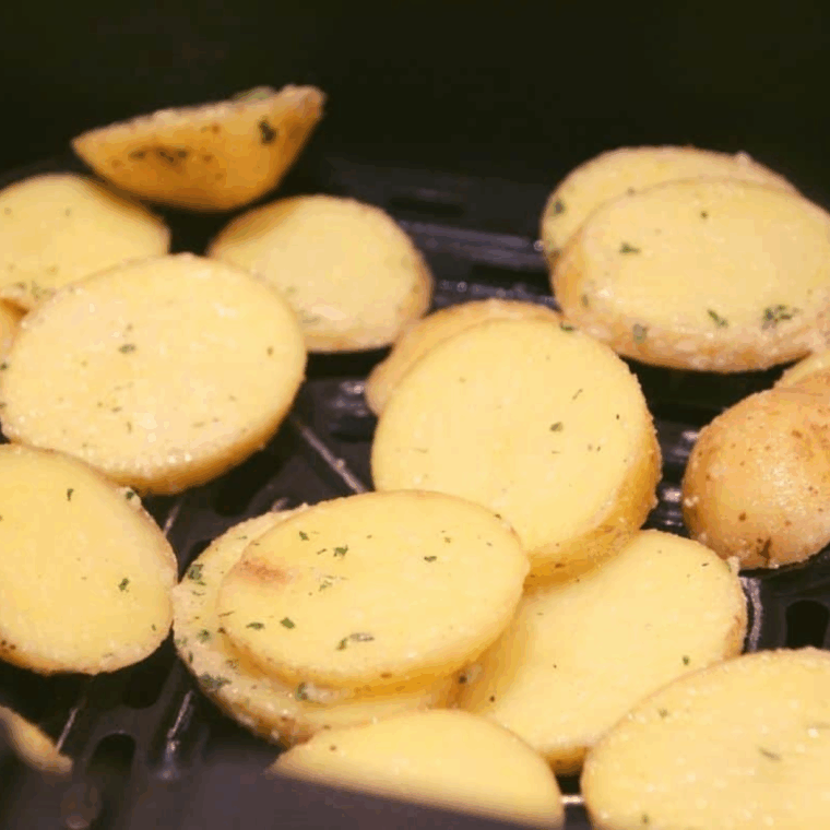 Seasoned potatoes placed in a preheated air fryer at 400°F, cooking until golden and crispy, flipped halfway through.