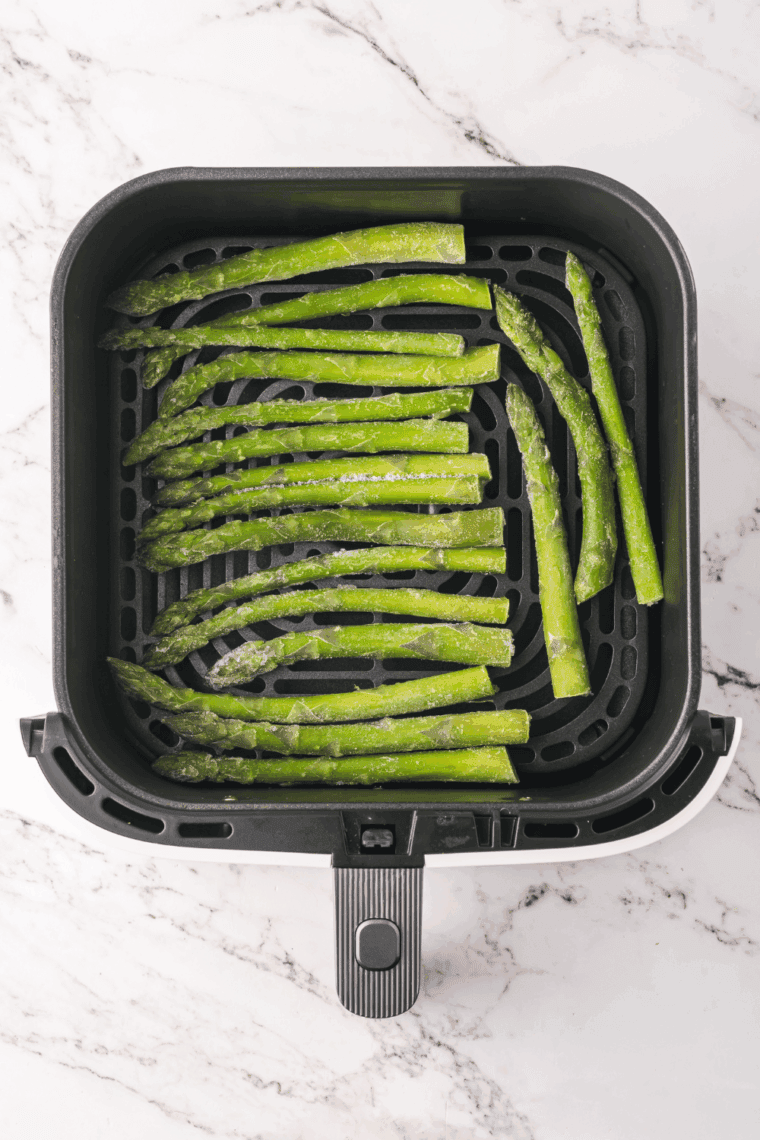 Pouring frozen asparagus spears directly from bag into a mixing bowl.