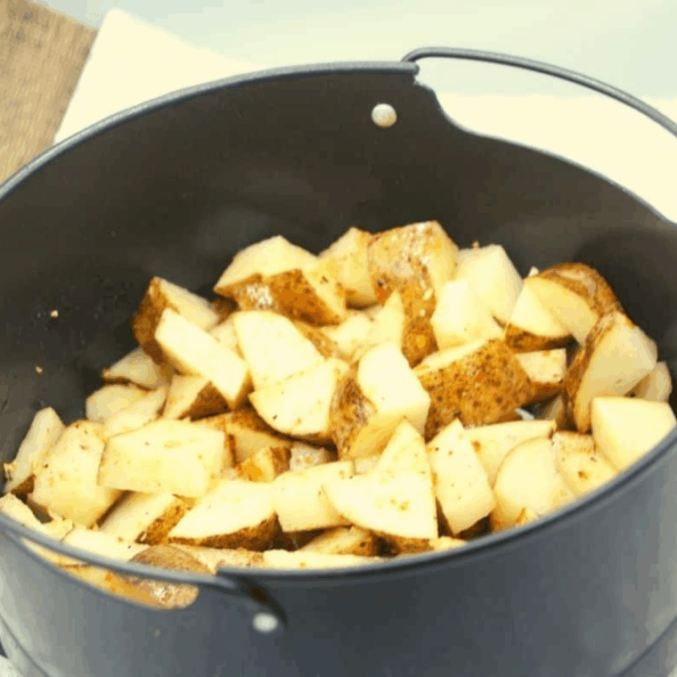 Seasoned diced potatoes placed in the Ninja Foodi crisper basket