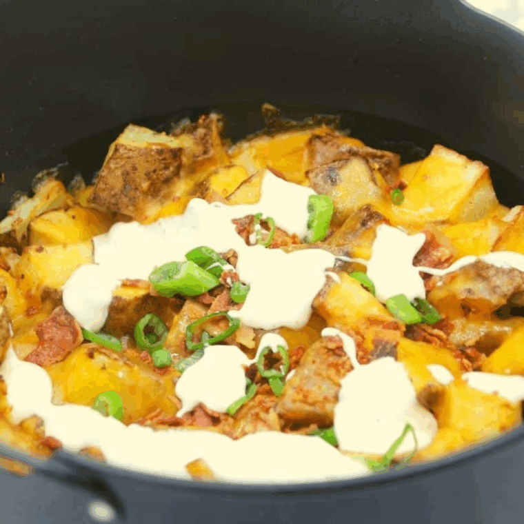 Loaded Ninja Foodi potatoes with melted cheese, crispy bacon, and sour cream