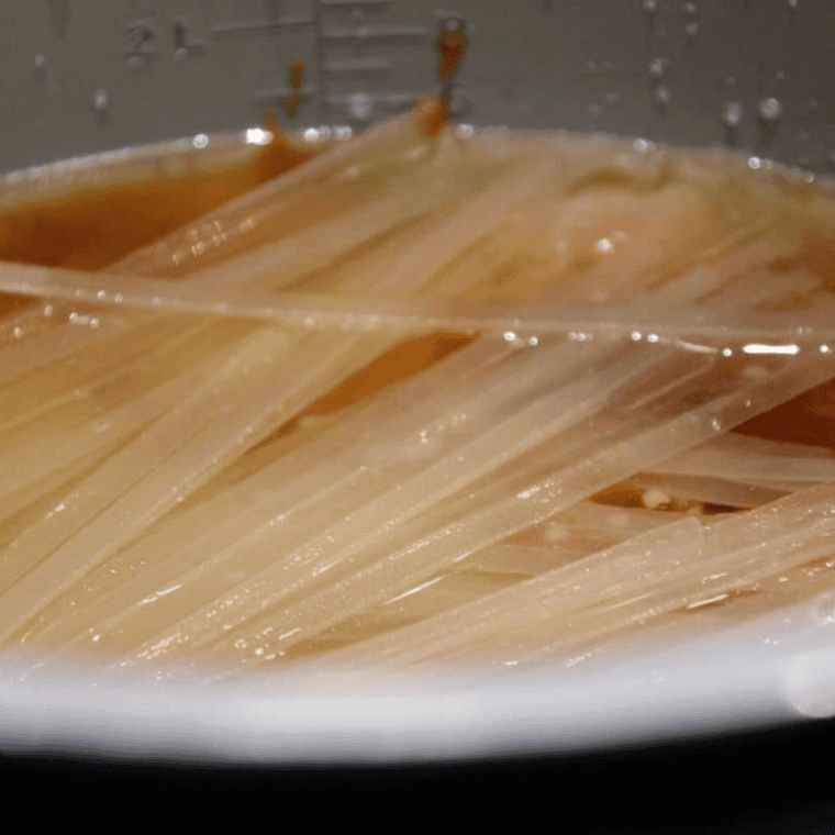 Soy sauce, pad thai sauce, water, and dry rice noodles added to the browned chicken in the Ninja Foodi pot