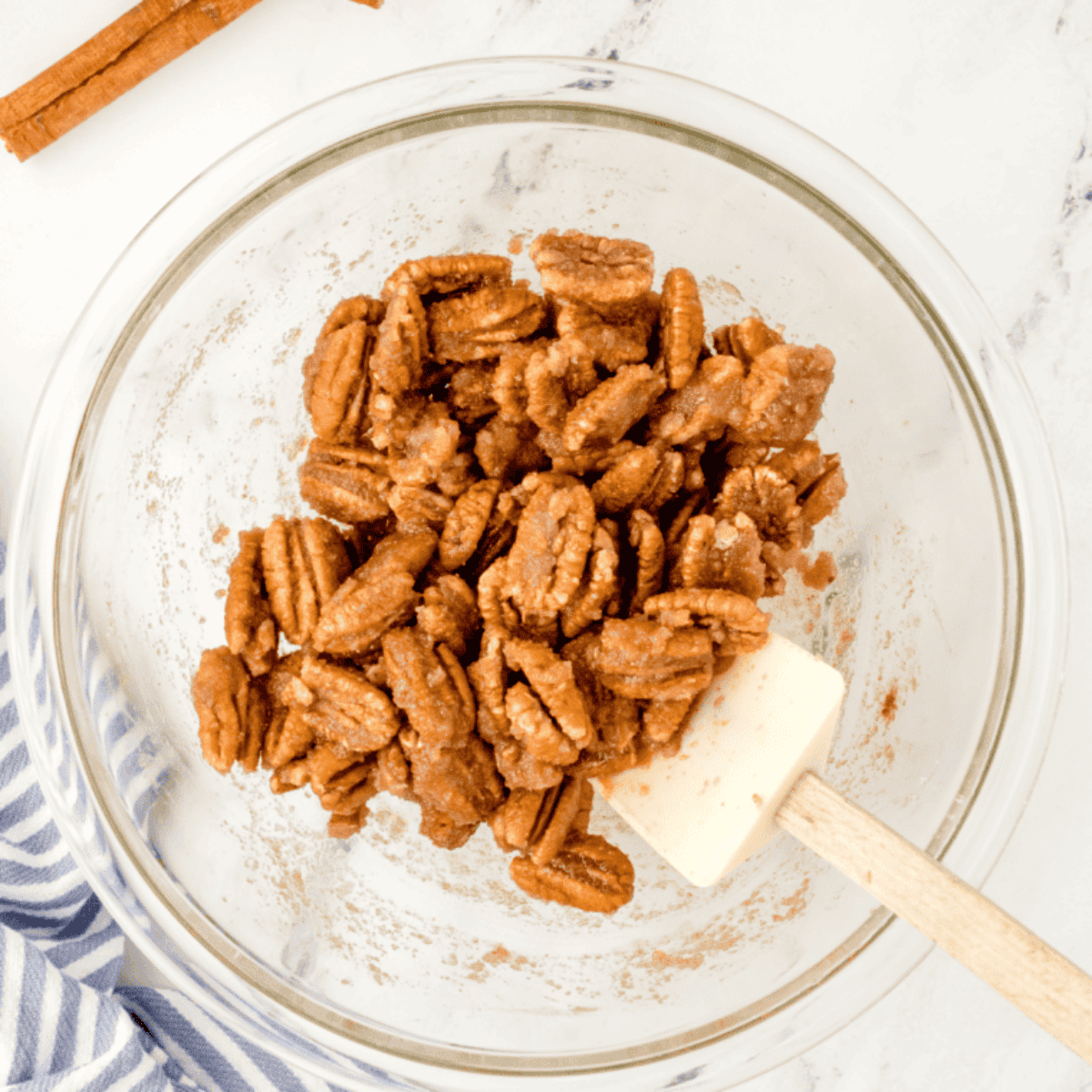 Mixing raw pecans with sugar, honey, cinnamon, vanilla, salt, and water in a large bowl until evenly coated.