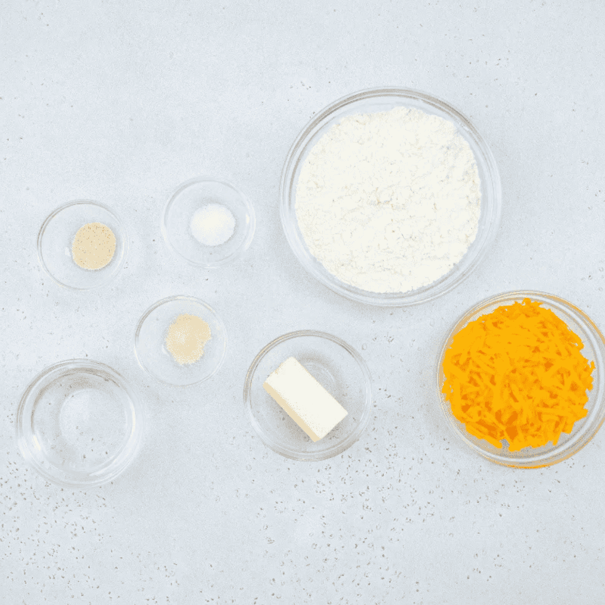 Ingredients to make air fryer Cheez-Its: cheddar cheese, flour, butter, and seasonings