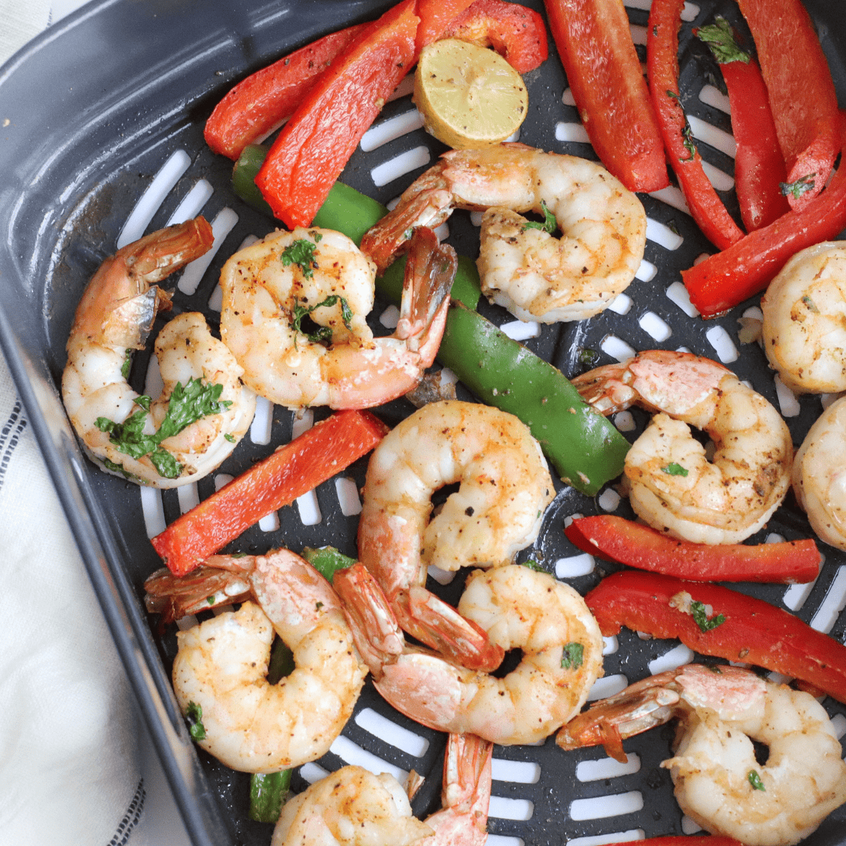 Juicy air fryer shrimp fajitas with colorful bell peppers and onions on a plate.