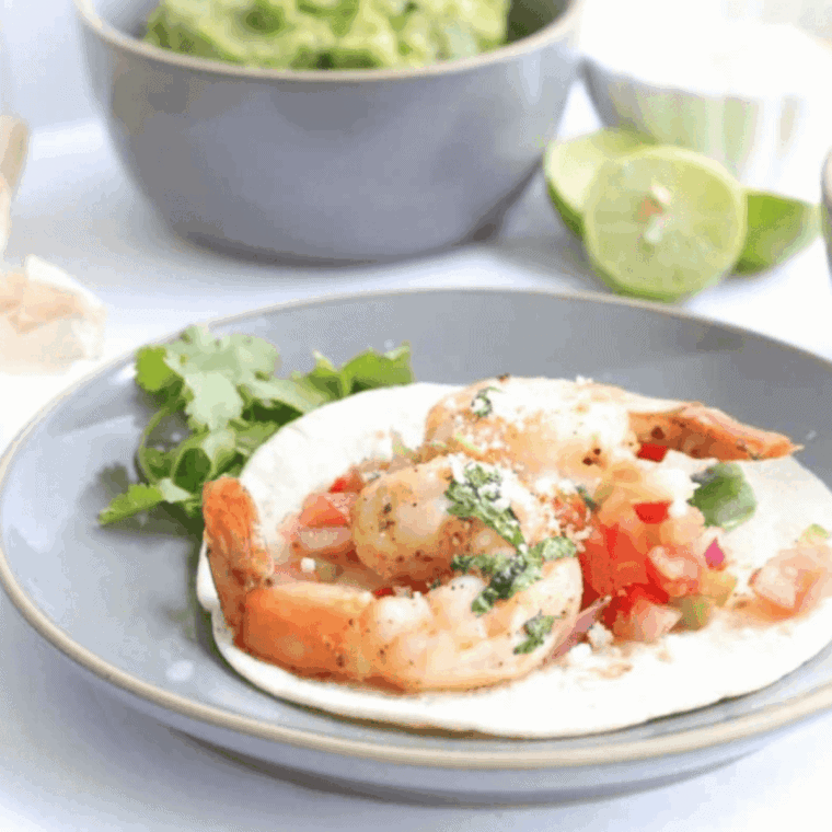 Air fryer shrimp fajitas with saut&eacute;ed bell peppers and onions served on a plate.