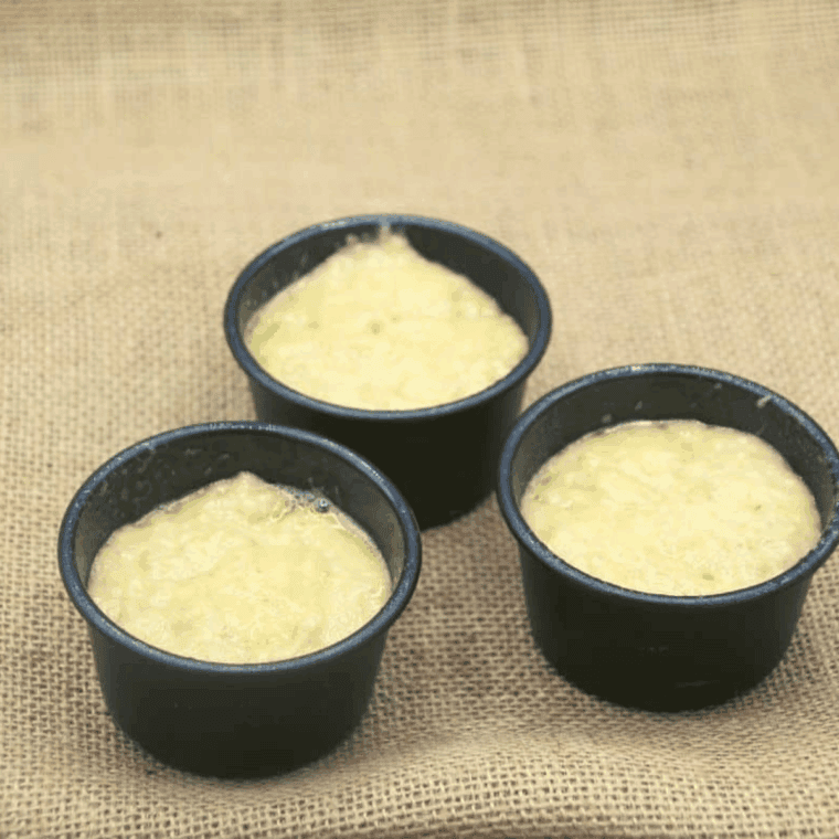 Filling greased muffin cups with banana bread batter