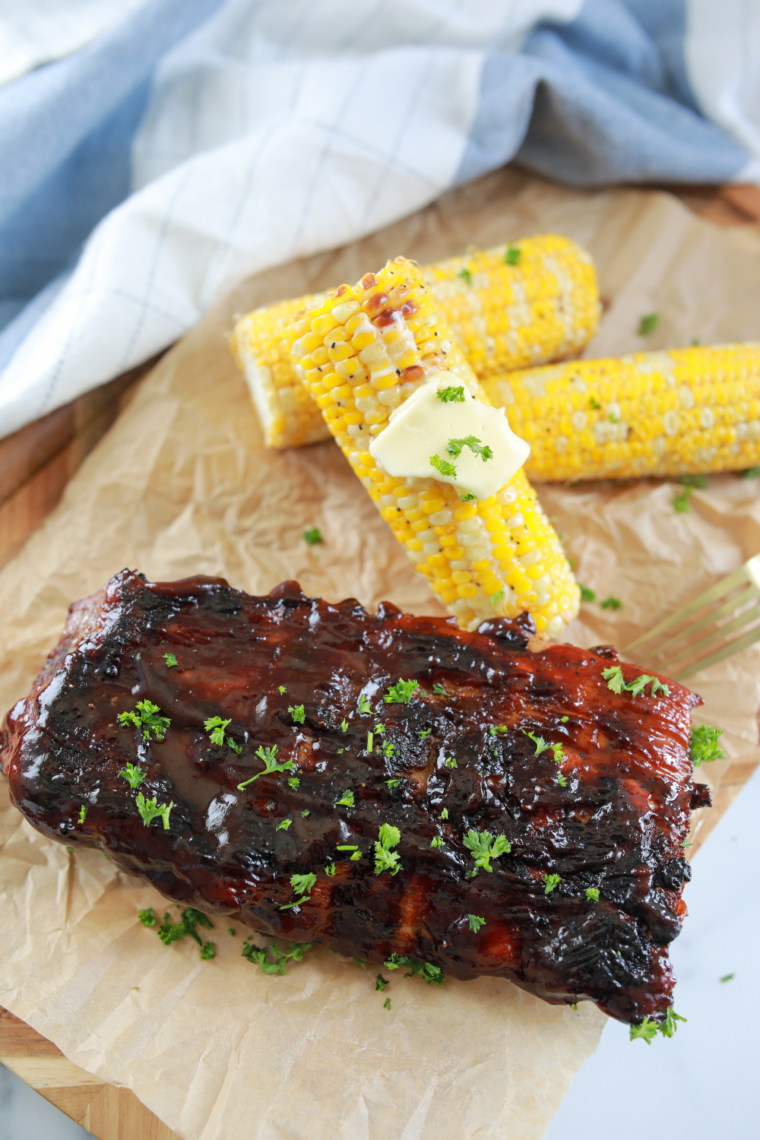 Fresh corn on the cob sizzling on a flat top griddle brushed with melted butter