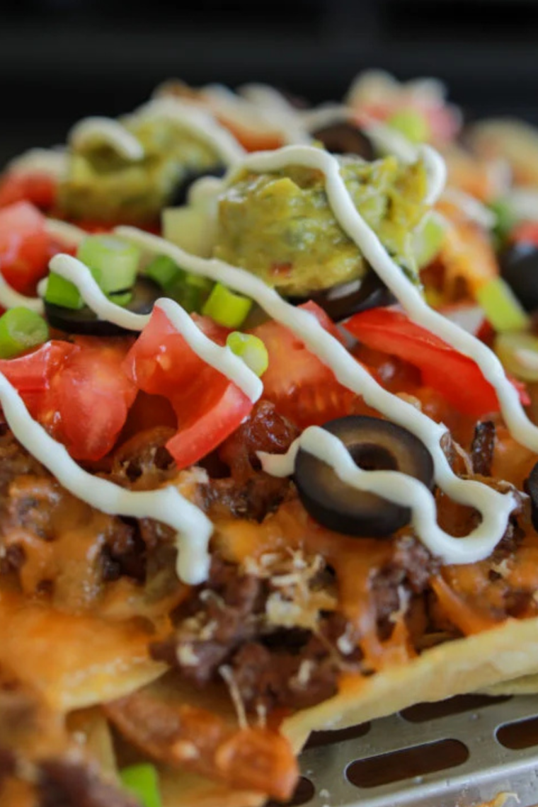 Griddle-made nachos piled high with beef, cheese, jalape&ntilde;os, olives, and salsa on a Blackstone flat top