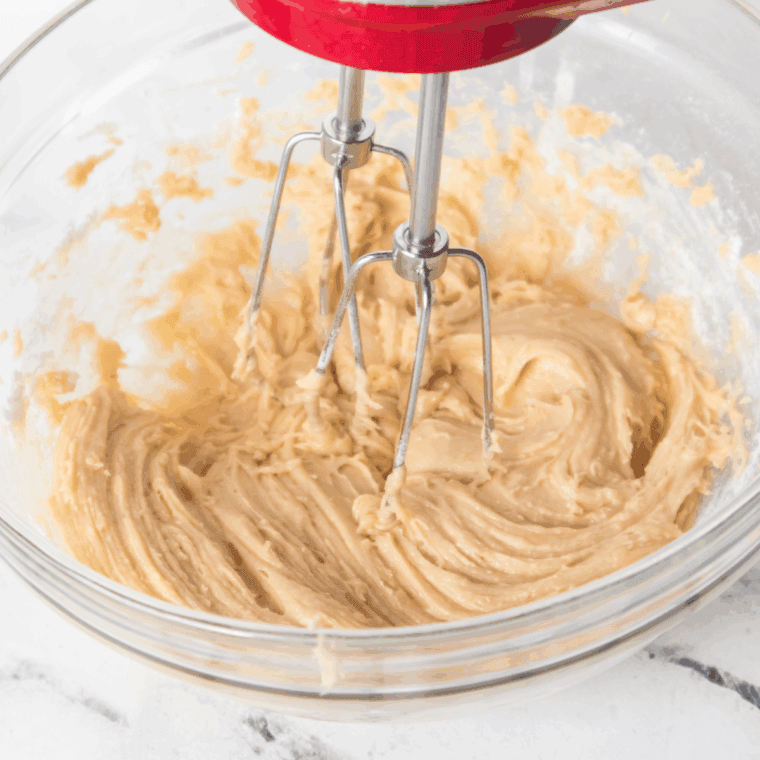 Mixing butter, brown sugar, and granulated sugar in a bowl until creamy, then adding vanilla, eggs, and lemon juice for cookie dough base.