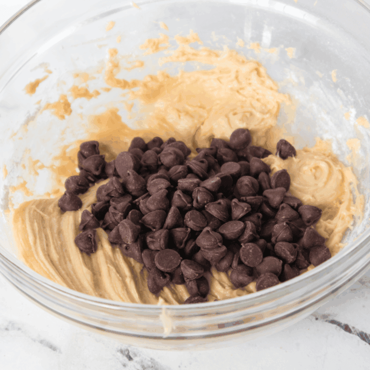 : Combining dry ingredients into cookie dough and folding in chopped walnuts and chocolate chips for rich, chunky texture.