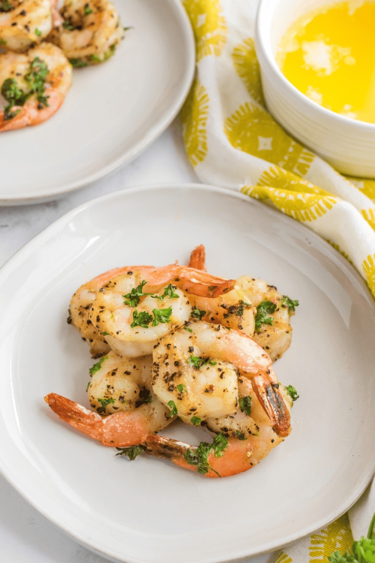 Crispy lemon pepper shrimp served on a plate with lemon wedges and garnished with herbs.