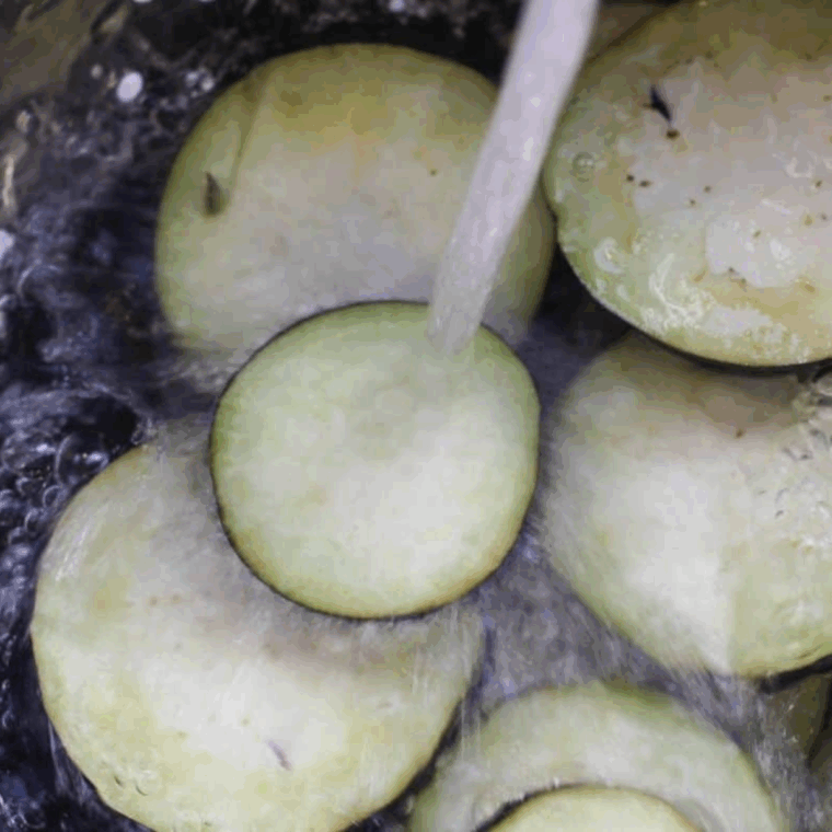 Rinsing salted eggplant slices under water and patting dry before cooking