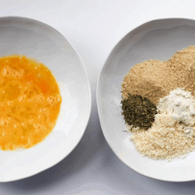 One bowl with beaten eggs. One bowl with gluten-free breadcrumbs, Parmesan, Italian seasoning, garlic powder, salt, and pepper.