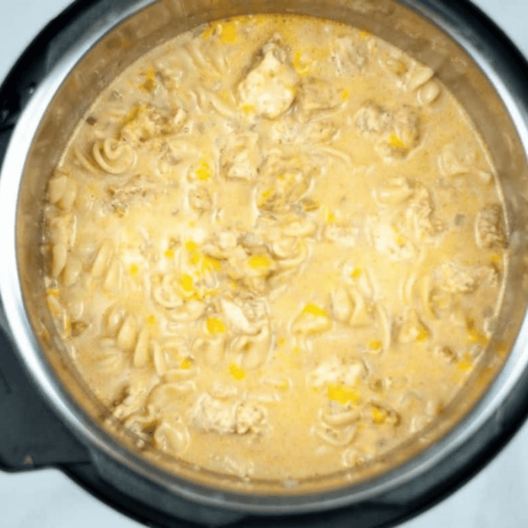 Stirring shredded cheese and heavy cream into cooked chicken fajita pasta in the Instant Pot.