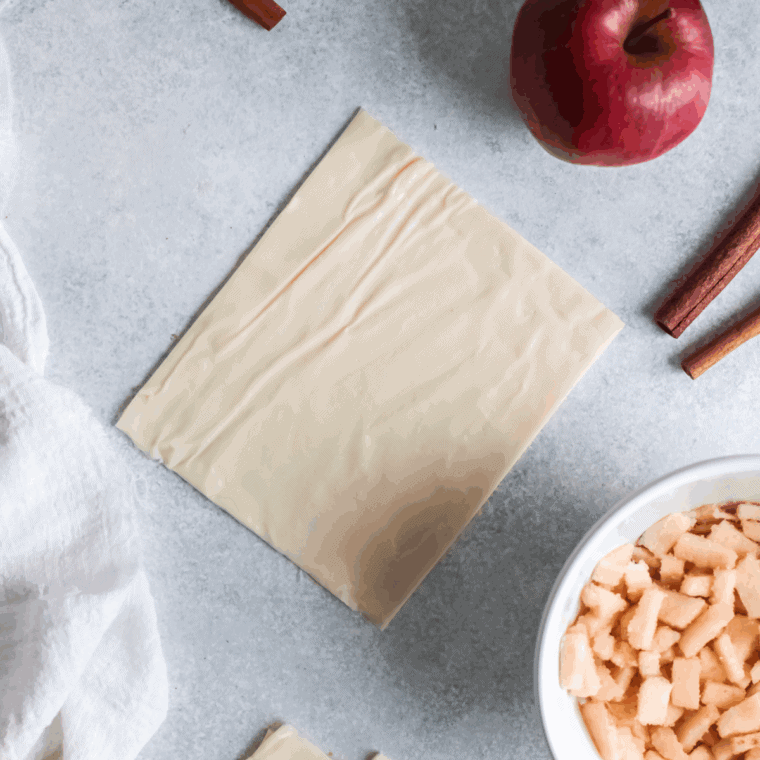 Unfolding and rolling puff pastry on a floured surface, then cutting into squares for turnovers.