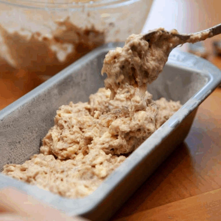 Pouring banana walnut pound cake batter into greased pan for air frying.