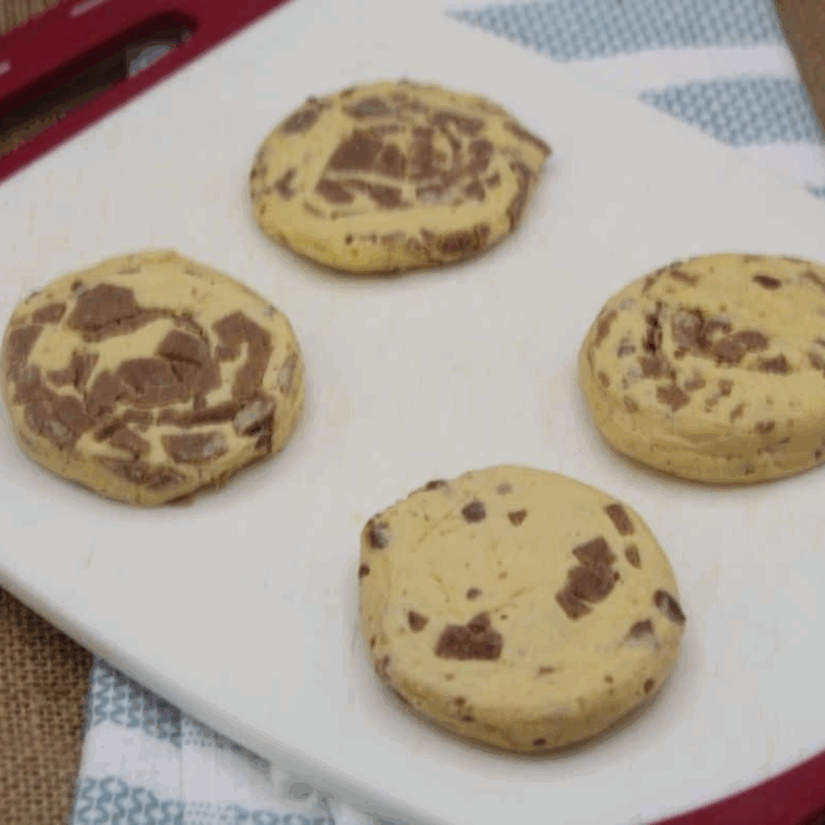 Flattening refrigerated cinnamon rolls on a surface, icing packet set aside.