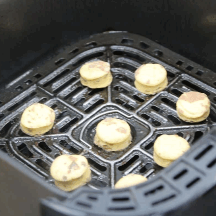 Cutting cinnamon roll bites with a biscuit cutter, then placing them in a sprayed air fryer basket to cook at 320°F for 3–4 minutes.
