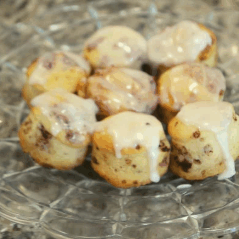 Golden, bite-sized cinnamon roll bites cooked in an air fryer and drizzled with glaze.