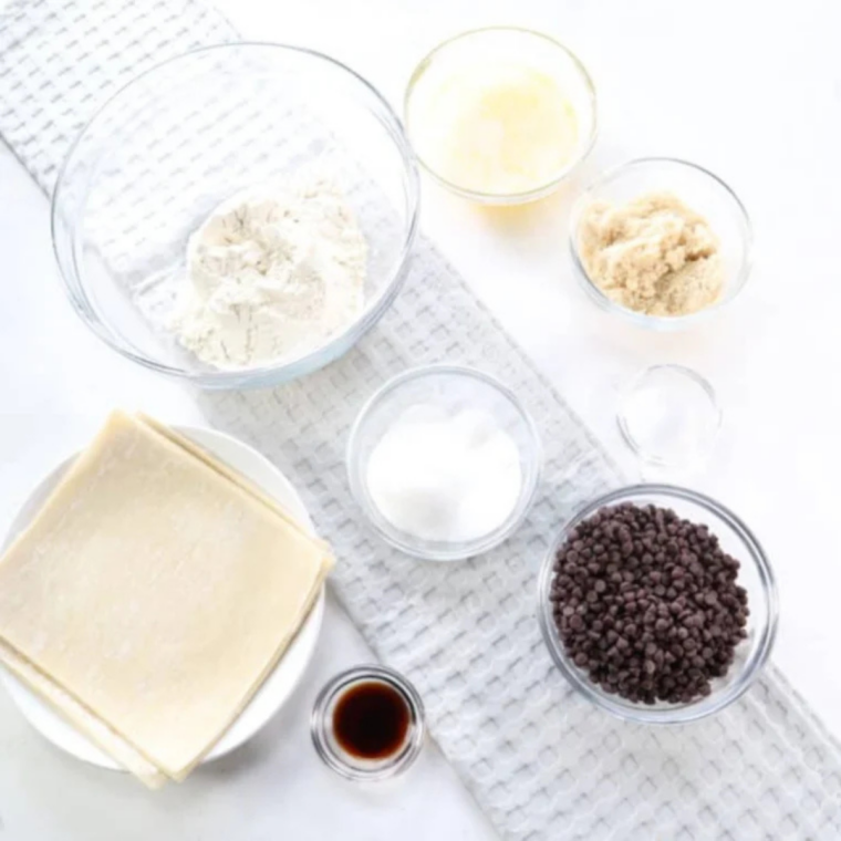 Ingredients for cookie dough egg rolls: egg roll wrappers, butter, brown sugar, granulated sugar, flour, salt, vanilla, and mini chocolate chips