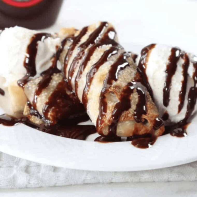 Hand holding a crispy cookie dough egg roll with chocolate chips melting from the center