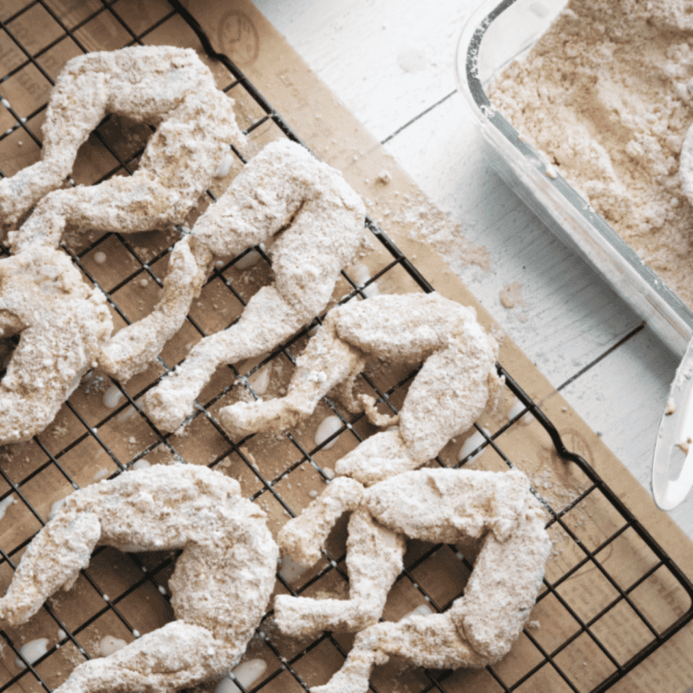 Golden, crispy air fryer frog legs on a plate, seasoned with salt and pepper, ready to serve with dipping sauce.