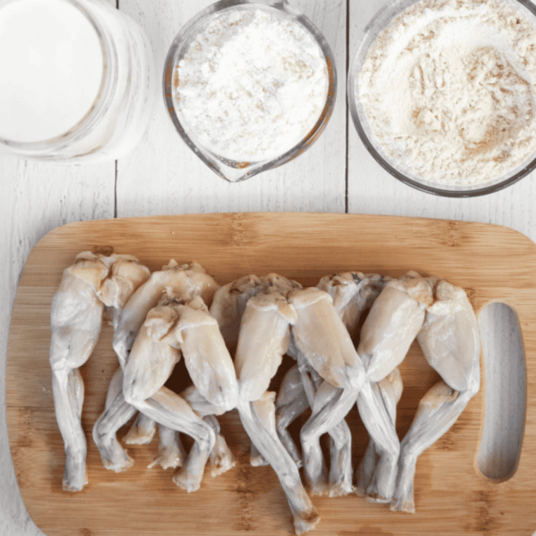 Frog legs soaking in buttermilk with Old Bay seasoning and garlic powder in a large bowl, covered and refrigerated to marinate.