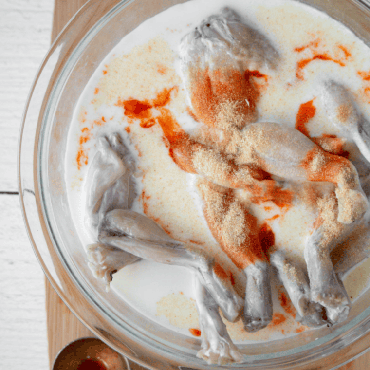 Mixing yellow cornmeal, all-purpose flour, and Old Bay seasoning in a bowl to prepare frog legs coating.