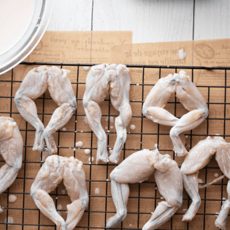 Frog legs being coated in cornmeal mixture after marinating, with optional double-dip for extra crispy coating.