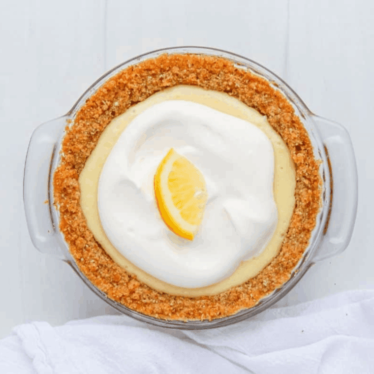Chilled air fryer lemon pie topped with whipped cream and garnished with a lemon slice, ready to serve.