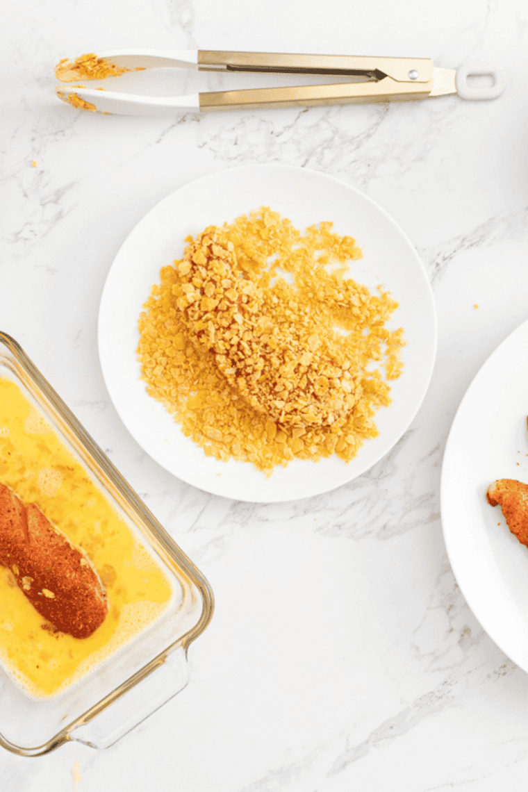 Chicken tenders fully submerged in dill pickle brine in a dish or zip-top bag, covered and refrigerated for marinating.