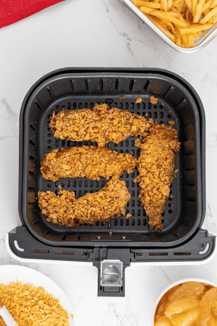 Air fryer preheating to 400&deg;F with setup of dredging station including flour, beaten eggs, and seasoned panko breadcrumb mixture in separate dishes.