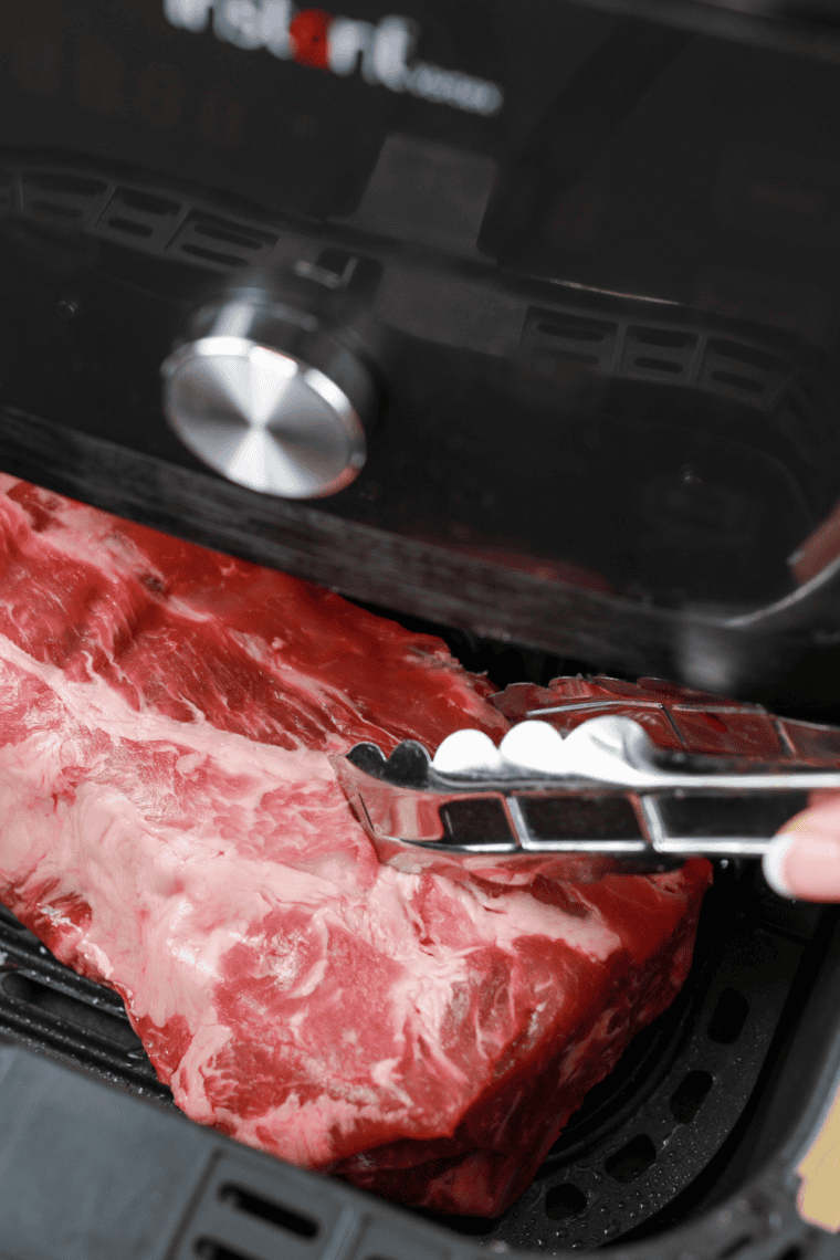 Ribs being rubbed with a spice mix of smoked paprika, garlic, onion, mustard, salt, and pepper.