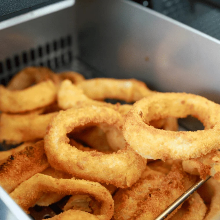 Frozen onion rings cooking on a Blackstone griddle until golden and crispy