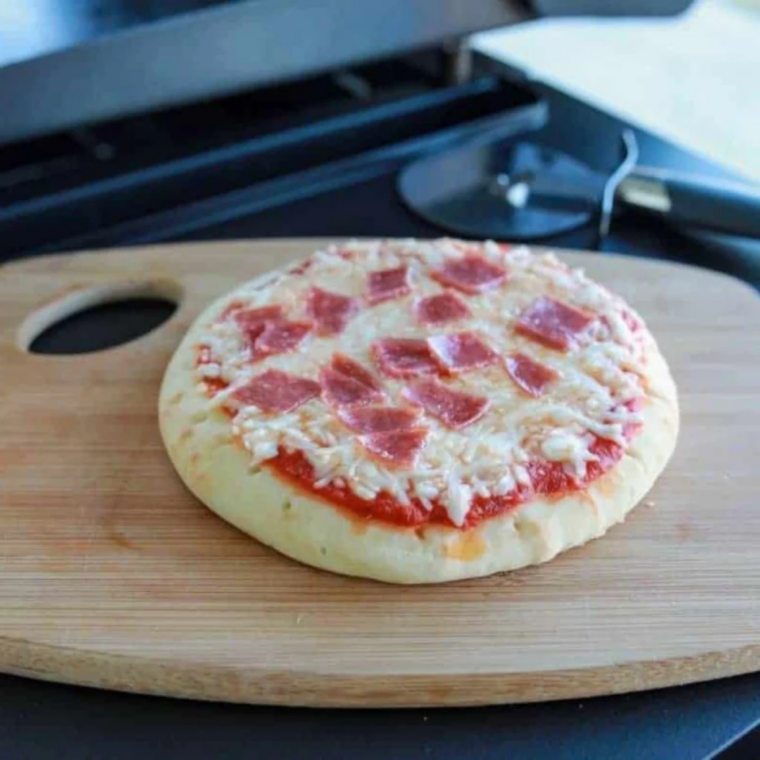 Finished Blackstone pepperoni pizza sliced on a cutting board.