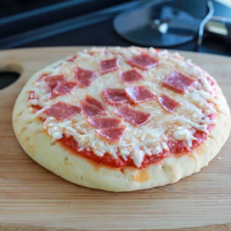 Close-up of pepperoni pizza cooking on a Blackstone griddle with bubbling cheese and crispy edges.