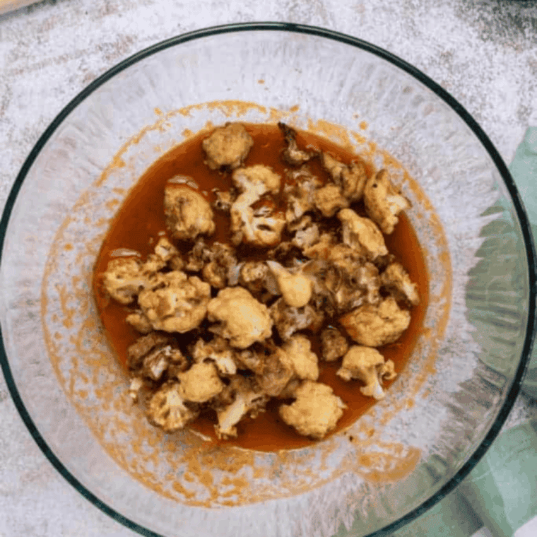Golden brown air-fried cauliflower being tossed in spicy Buffalo sauce for crispy, flavorful bites.”