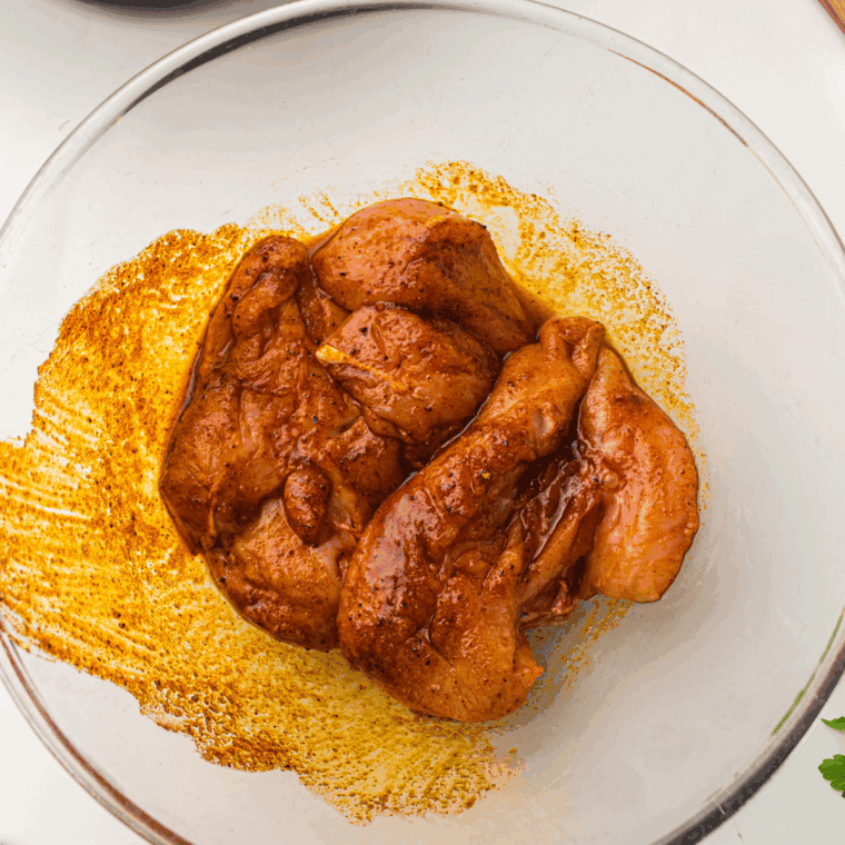 Chicken breasts in a large bowl coated with olive oil, lemon juice, minced garlic, Italian seasoning, red pepper flakes, salt, and black pepper, ready to marinate.