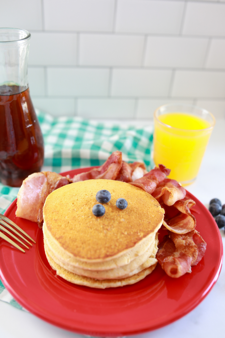 Stack of fluffy Blackstone griddle pancakes golden brown on a plate with butter melting and syrup poured over the top.