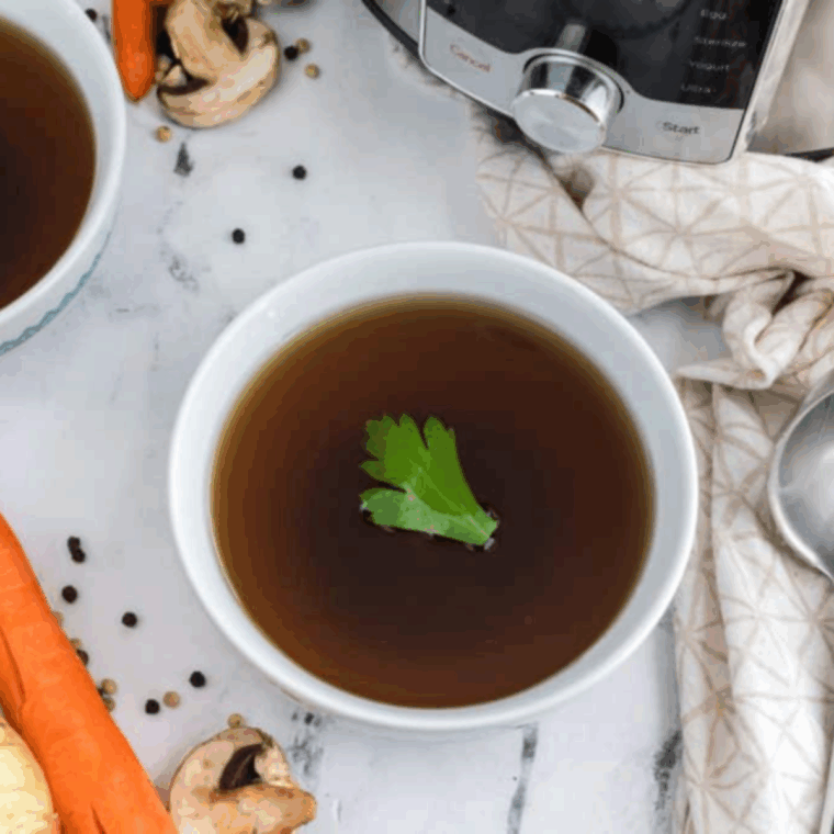 Homemade, clear low sodium vegetable stock simmering in a pot with carrots, celery, onion, and fresh herbs.