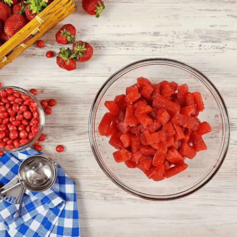 Separating a frozen strawberry Skittles pop from a sheet by gently bending it back and forth.