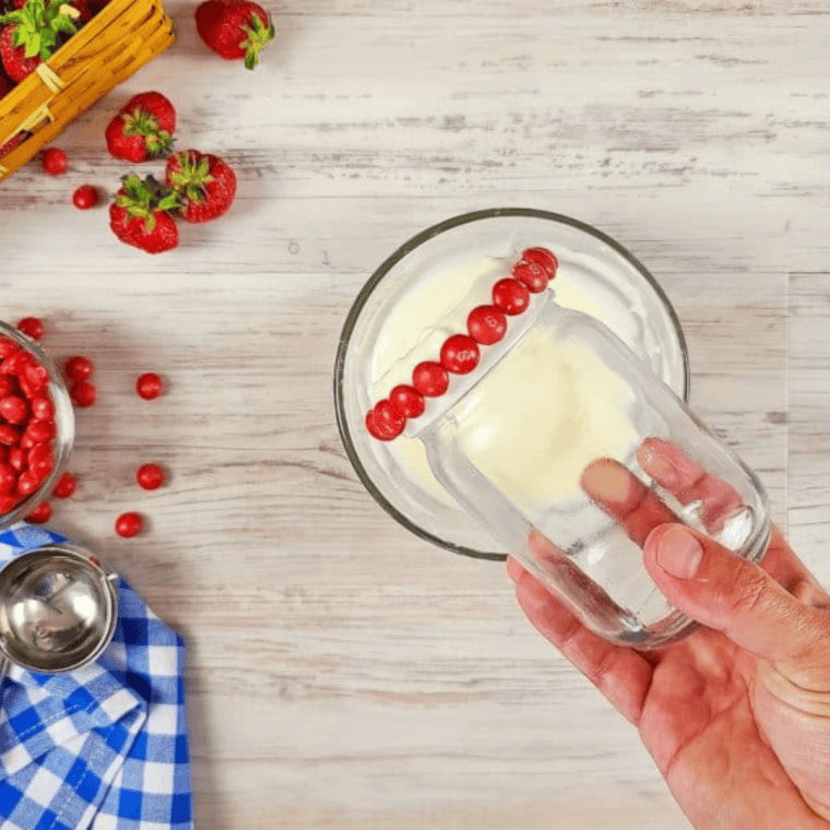 Rimming a milkshake glass with slightly cooled white chocolate for candy decoration.