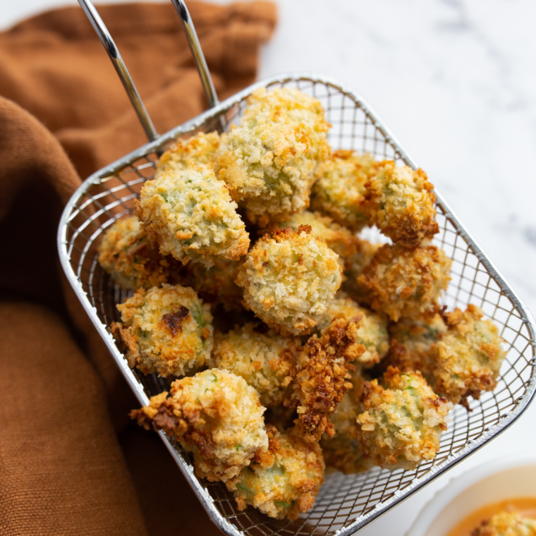 Crispy breaded frozen okra air fried until golden, served on a white plate with ranch dip