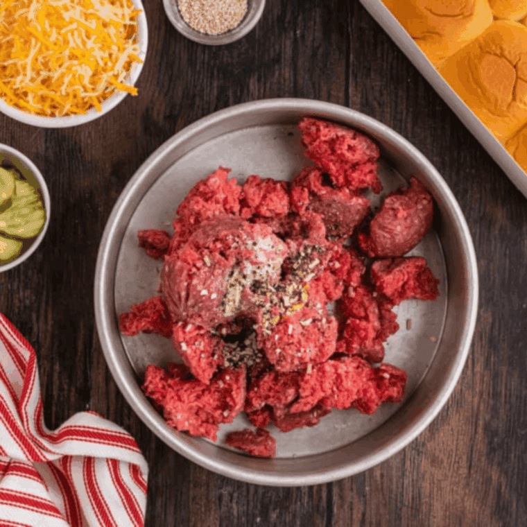 Crumble ground beef into a pan and season with garlic salt, onion flakes, and black pepper, mixing evenly.