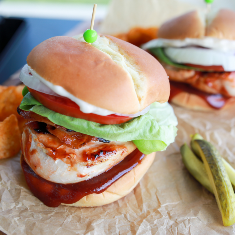 Toast the buns and build: BBQ chicken burger assembled with lettuce, tomato, bacon, onion, and barbecue chicken on a toasted bun.