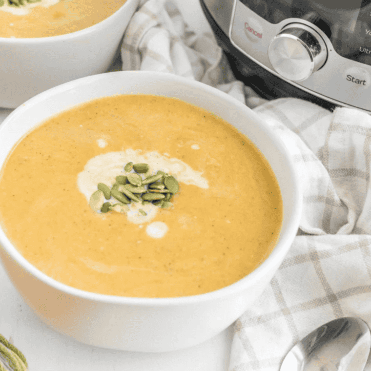 Deep orange butternut squash soup made with coconut milk and sweet potato, served with crusty bread