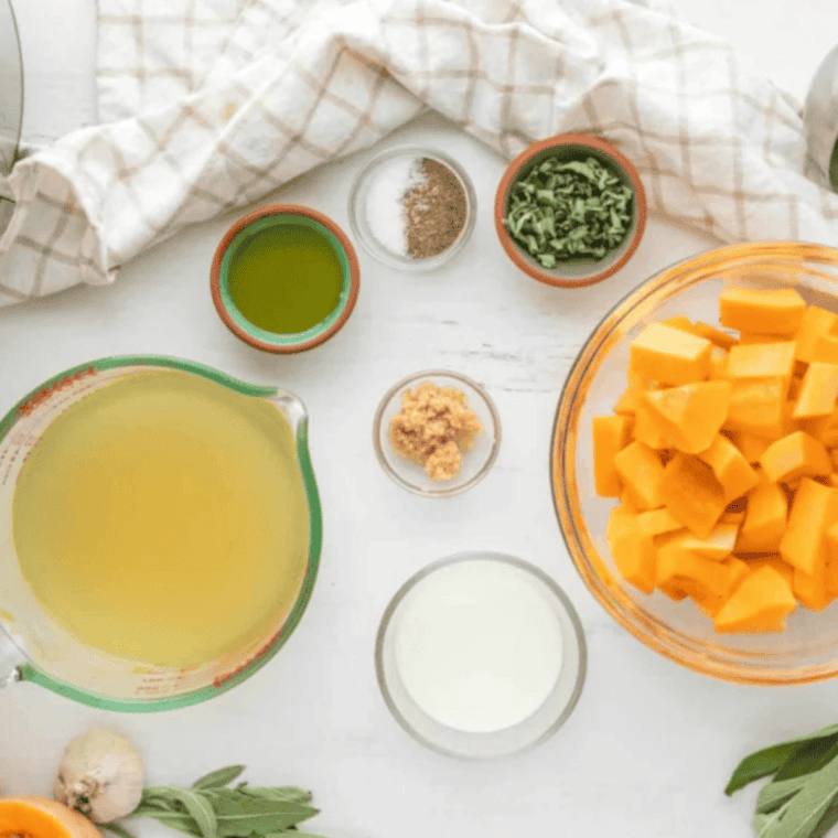 Butternut squash, sweet potato, onion, garlic, fresh ginger, and canned coconut milk laid out for copycat Costco butternut squash soup
